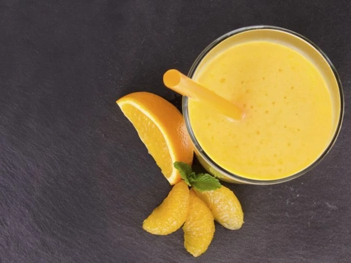 sliced oranges, how to make a mango smoothie, yellow straw, black countertop