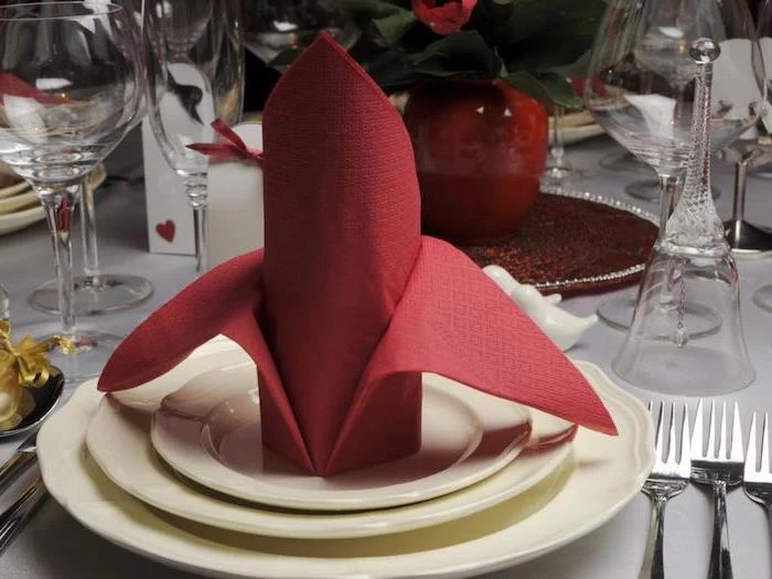 red paper napkin, on white plates, silverware around, how to fold cloth napkins, wine glasses