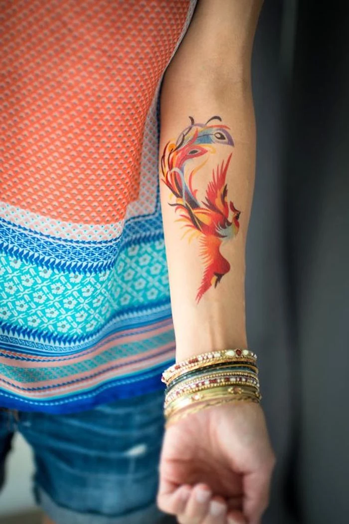 watercolour phoenix, with spread wings, forearm tattoo, leg tattoos for girls, colourful top, denim shorts