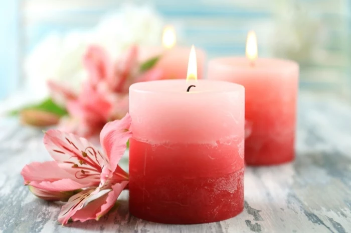 diy candles, small round candles, in shades of pink, pink flowers around them, on a wooden table