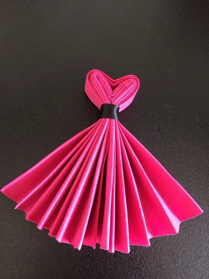pink napkin, folded in the shape of a dress, tied with a black ribbon, how to fold cloth napkins