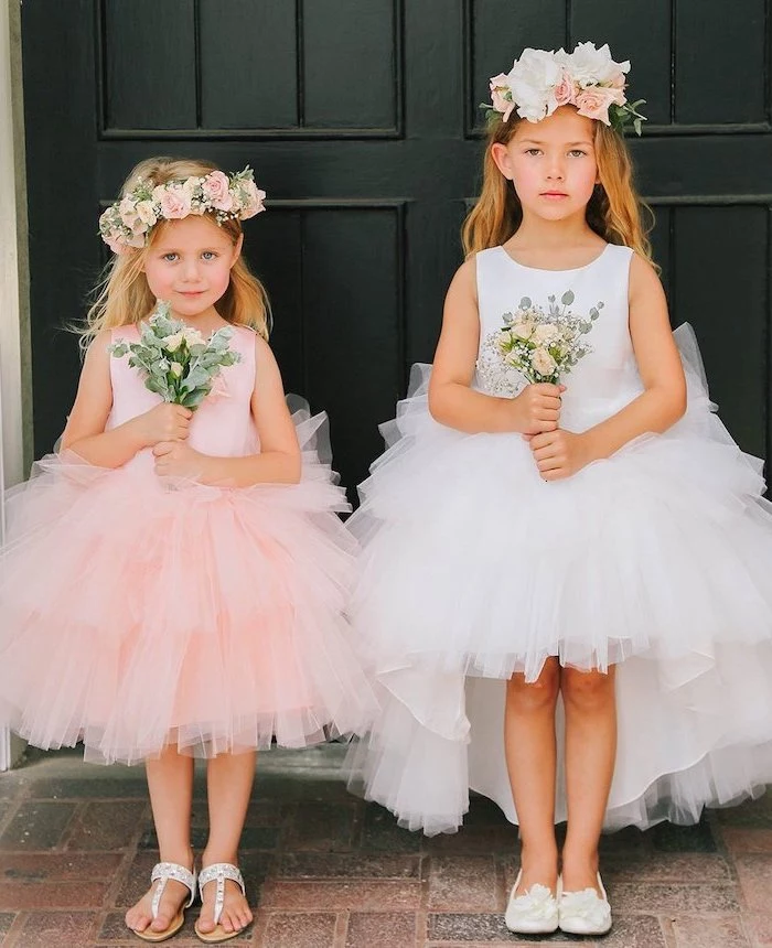 two girls, one with white tulle dress, the other with pink tulle, little girl dresses, white sandals, flower crowns