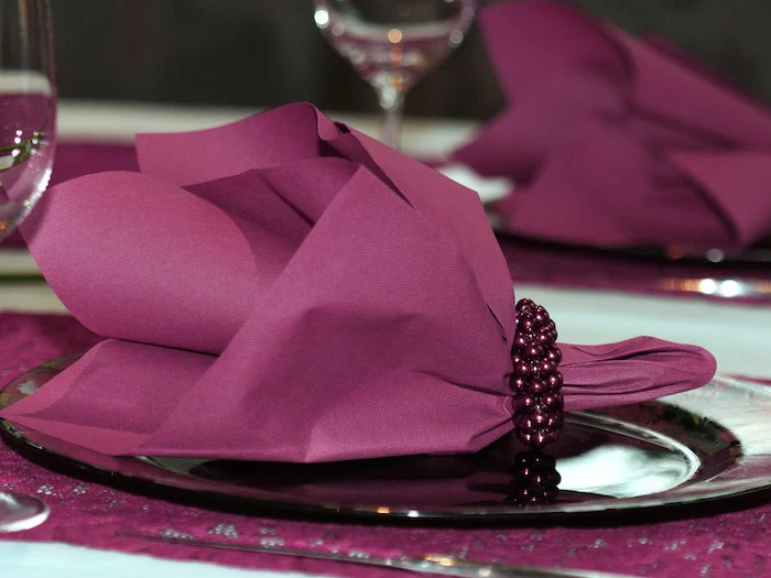 purple paper napkin, purple pearl ring around it, on a purple plate, napkin folding ideas