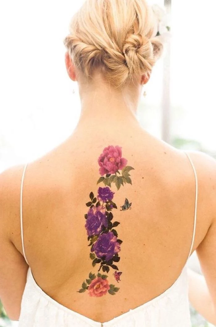 blonde hair, pink and purple flowers, back tattoos, small tattoos with meaning, white top
