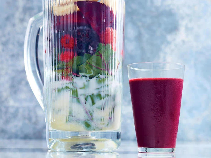 large pitcher, filled with fruits and milk, tall glass next to it, how do you make a smoothie