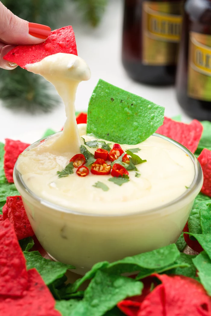 red and green tortilla chips, veggie appetizers, sour cream in a glass bowl