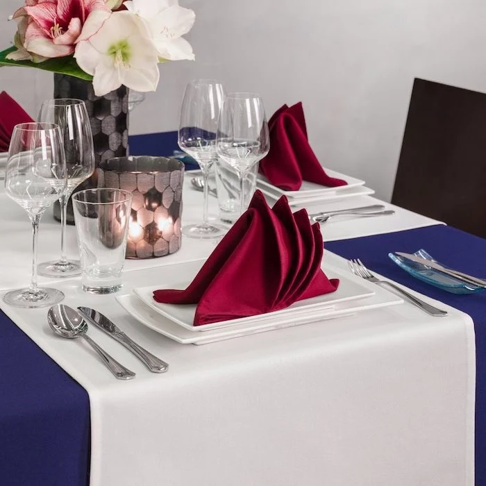 flower bouquet, how to fold dinner napkins, red folded napkins, on white plates, blue table cloth