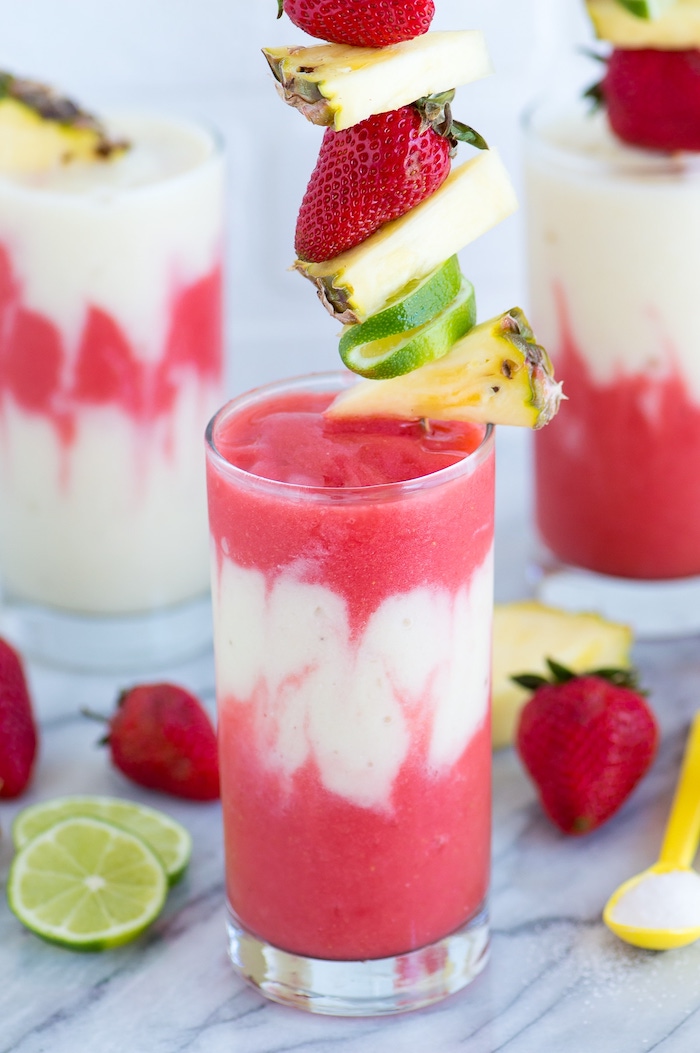 layered smoothie, fruit smoothie recipes, pineapple and strawberry slices, on a wooden skewer
