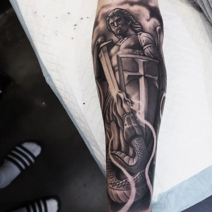the archangel michael, slaying the snake, religious theme, tattoo ideas for men arm