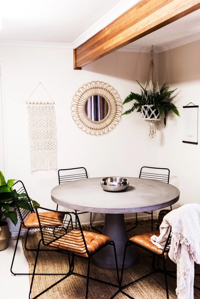 woven wall tapestry, round table, black metal chairs, leather cushions, white walls, potted plants