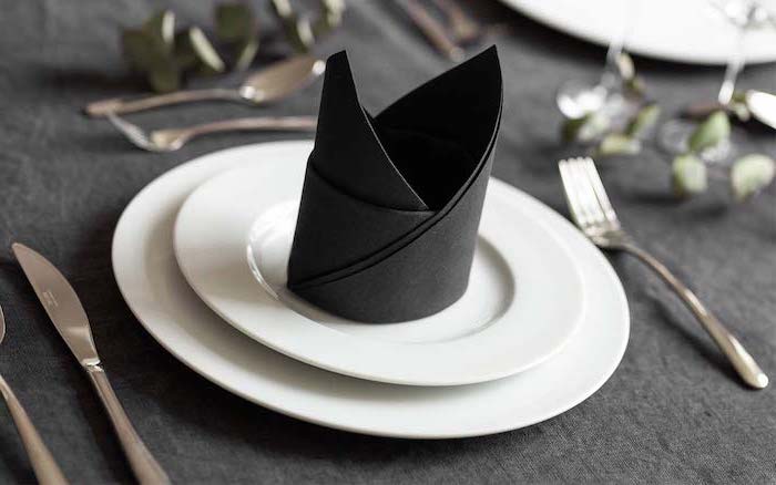 black napkin, crown shaped, how to fold napkins fancy, white plates, black table cloth
