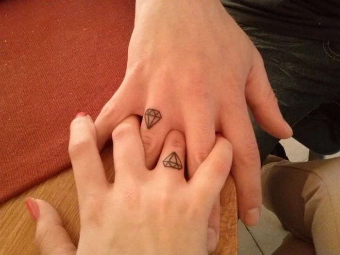 his and hers matching tattoos, diamond on the finger, intertwined fingers, wooden table