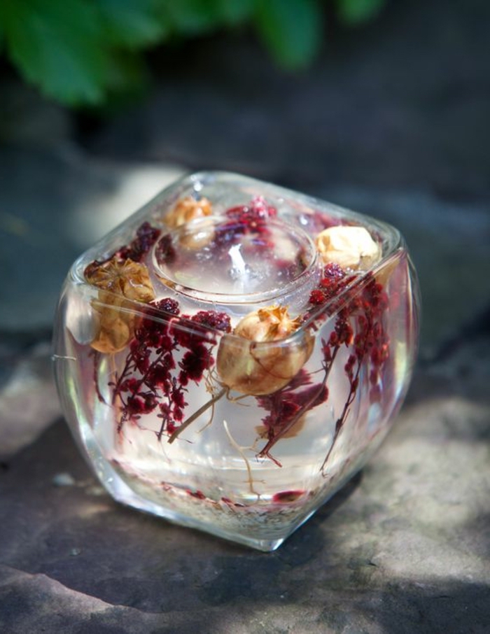small round glass, inside a large square vase, filled with candle wax, dried flowers, how to make candles