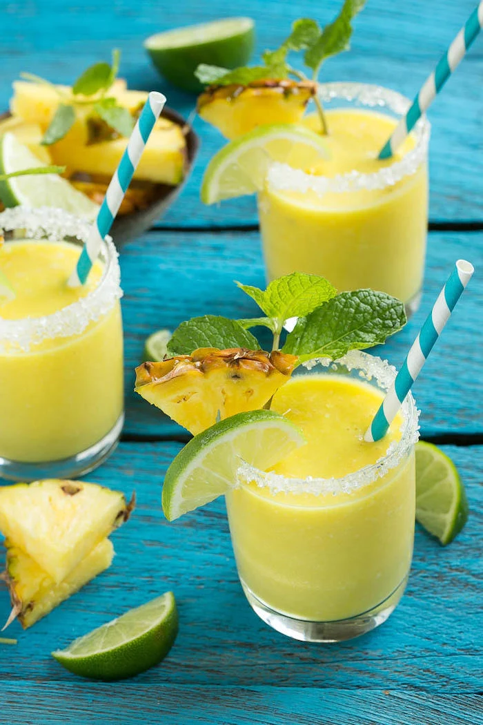 sugar on the rim, lime and pineapple slices, healthy breakfast smoothie recipes, mint on top, blue wooden table