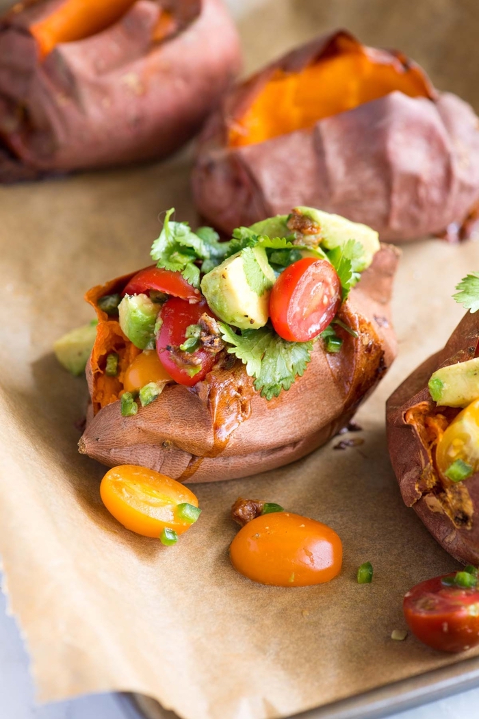 sweet potatoes, filled with cherry tomatoes, avocado and herbs, vegetarian finger food, baking paper