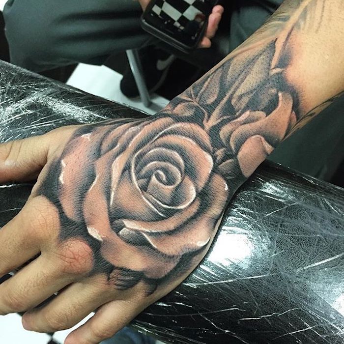 large rose, hand tattoo, black arm rest, meaningful tattoo ideas