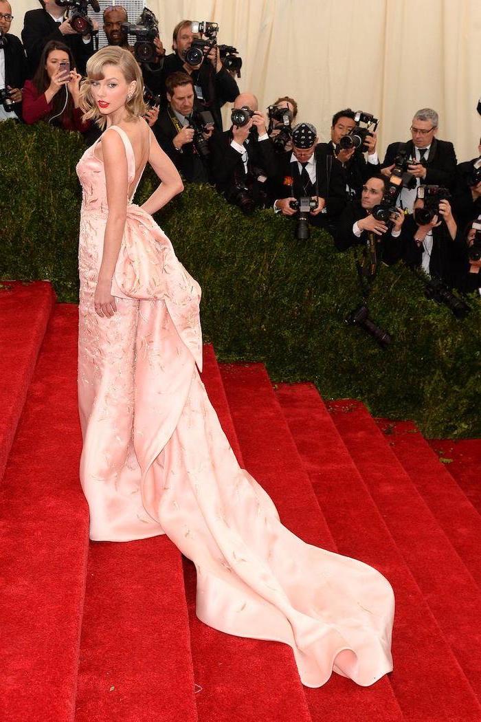 met costume institute, taylor swift, light pink dress, long train, large bow on the back, on the red carpet