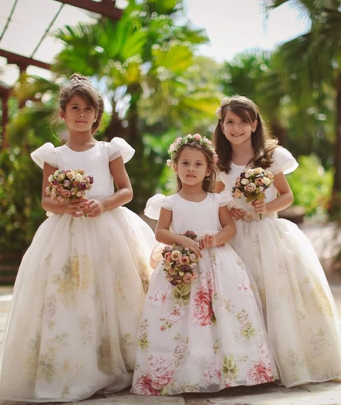 little girl dresses, three girls, with floral tulle dresses, brown hair, flower bouquets, greenery in the background
