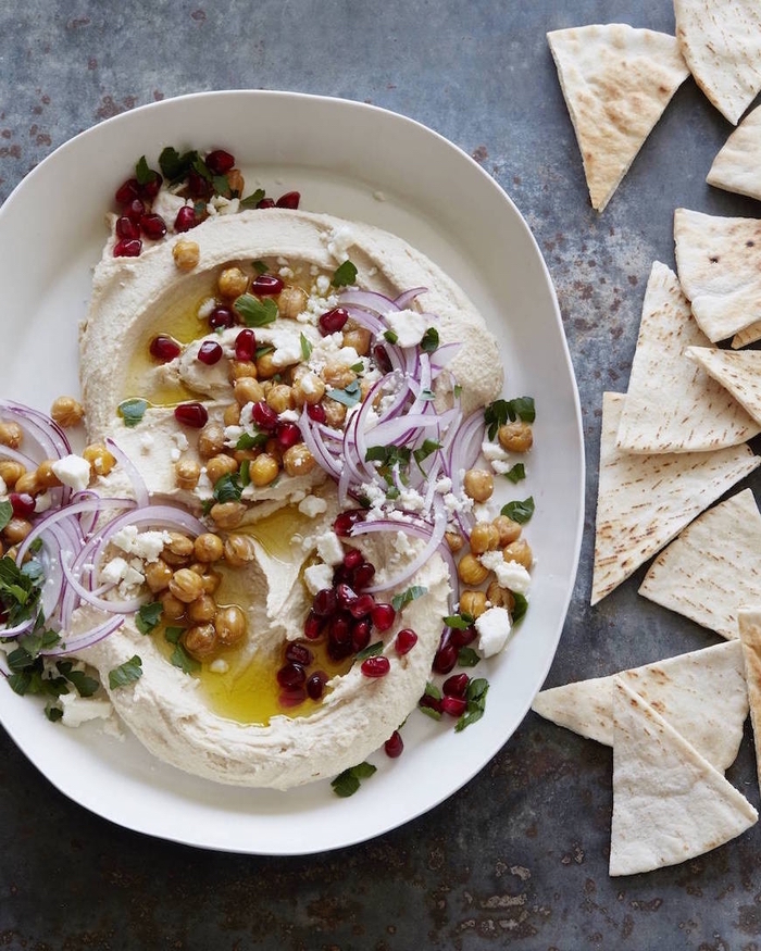 vegetarian super bowl recipe, hummus with chickpeas, onion and pomegranate, in a white plate
