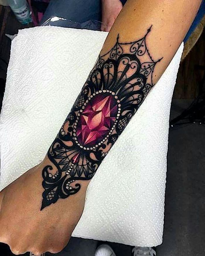 white paper, small arm tattoos, large red crystal, arm tattoo