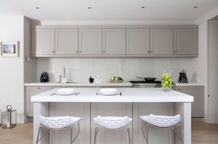 white bar stools, grey cabinets, white backsplash, wooden floor, floating kitchen island