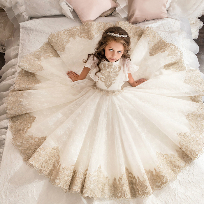 little girl sitting on a bed, white and ivory lace, flower girl shoes, brown wavy hair, white tiara