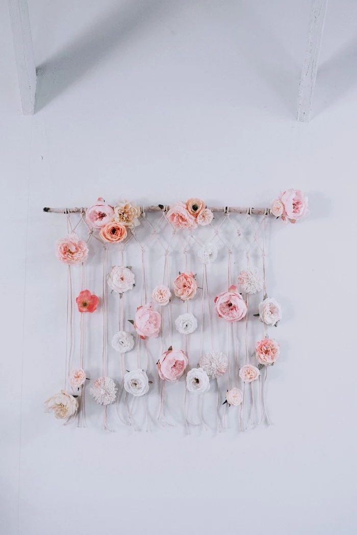 macrame wall hanging tutorial, intertwined with pink and white flowers, white wall