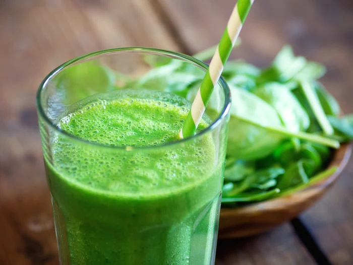 spinach in a wooden bowl, how to make a green smoothie, green and white paper straw