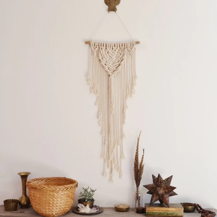 white wall, wooden basket, wooden table, macrame wall hanging knots, metal vase, potted succulent