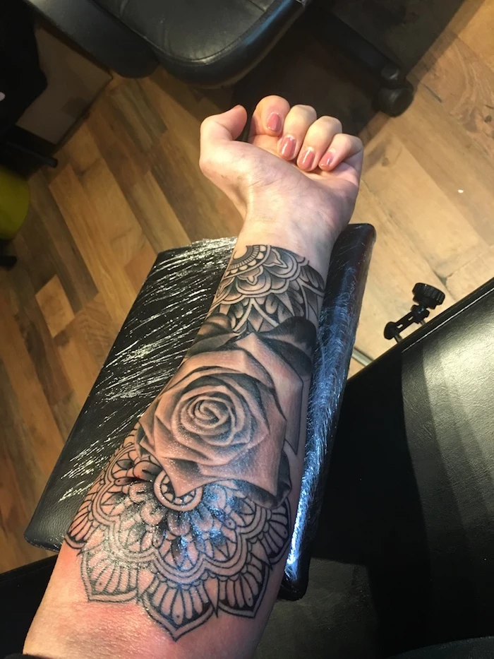 mandala roses, forearm tattoo, tattoos with deep meaning, black leather chair, wooden floor