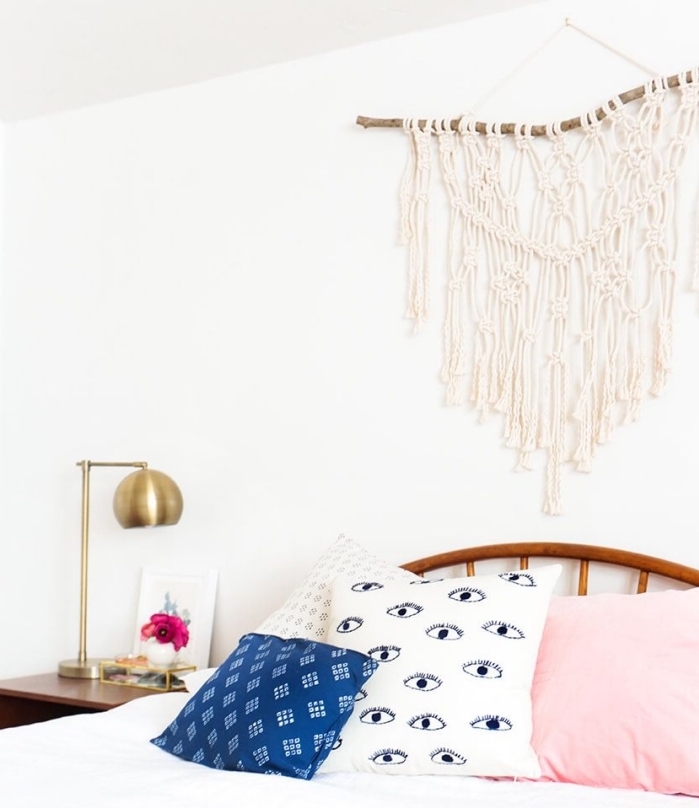 white pink and blue throw pillows, macrame wall hanging, white wall, brass metal lamp