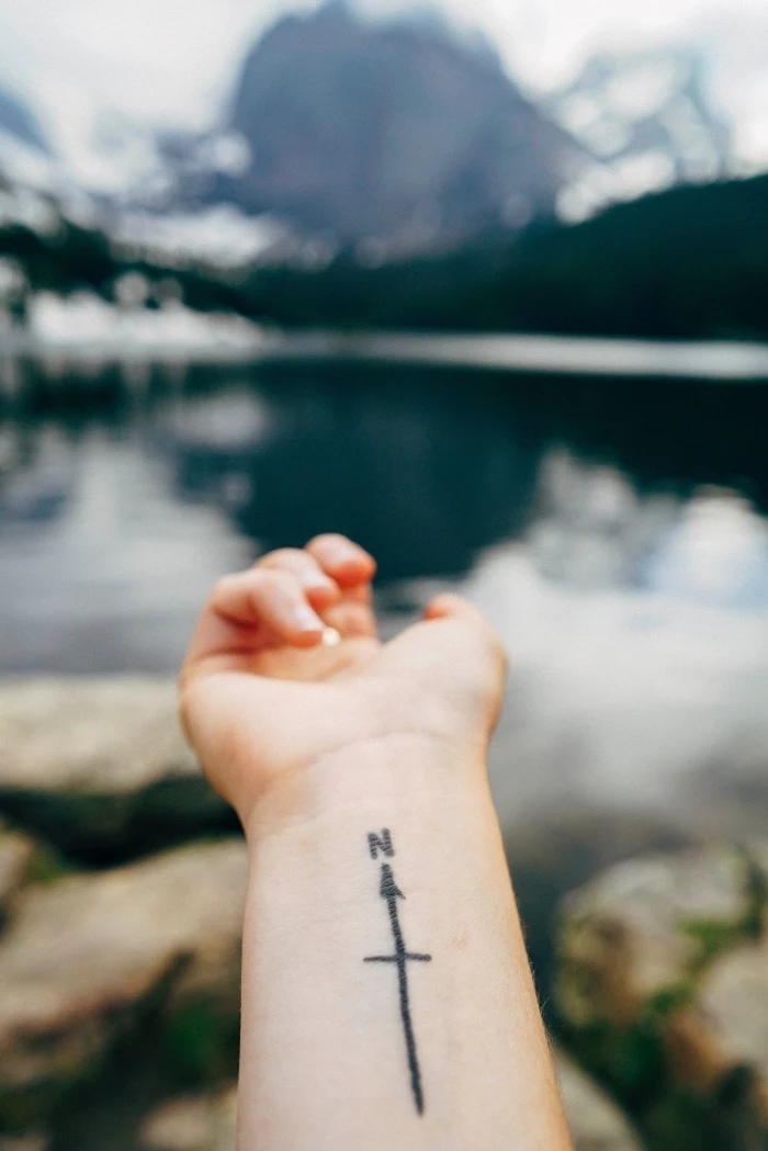 compass arrow, pointing north, wrist tattoo, mountain landscape, tattoo placement