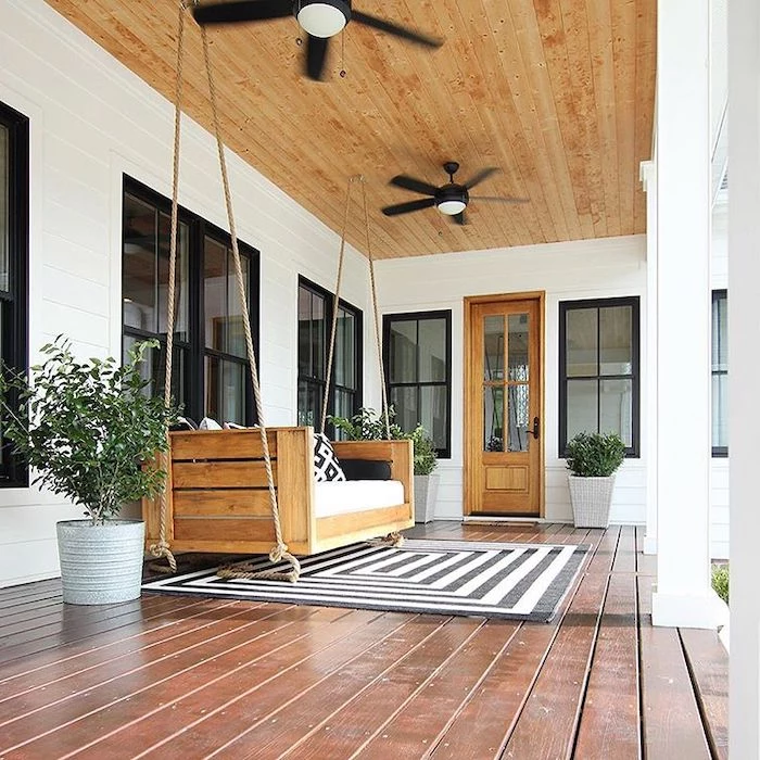 wooden swing, front porch decorating ideas, white cushions, black and white rug, wooden ceiling and floor