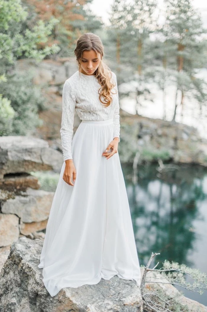 dark blonde hair, in a low ponytail, fitted wedding dresses, woman standing on rocks, next to a lake