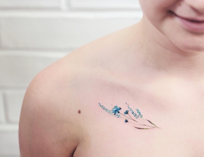 blue flowers, shoulder tattoo, inner bicep tattoo, white brick wall