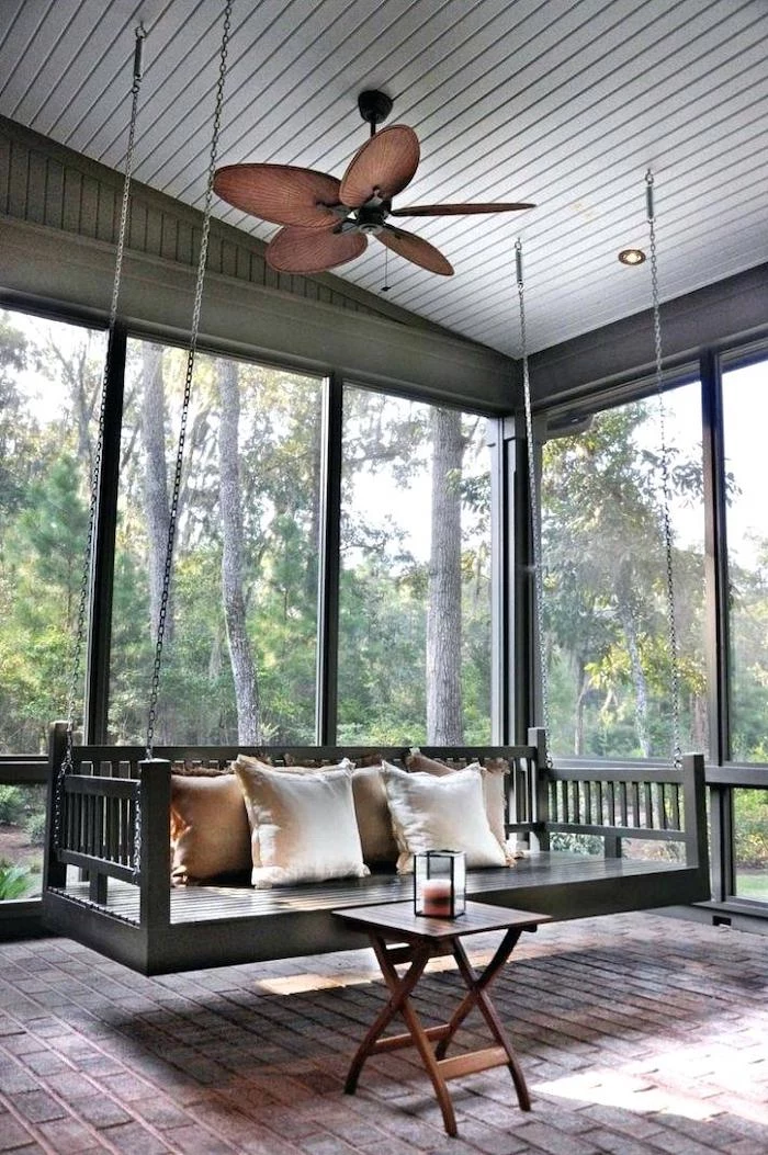 ceiling fan, front porch designs, wooden swing, held by metal chains, small table, screened in