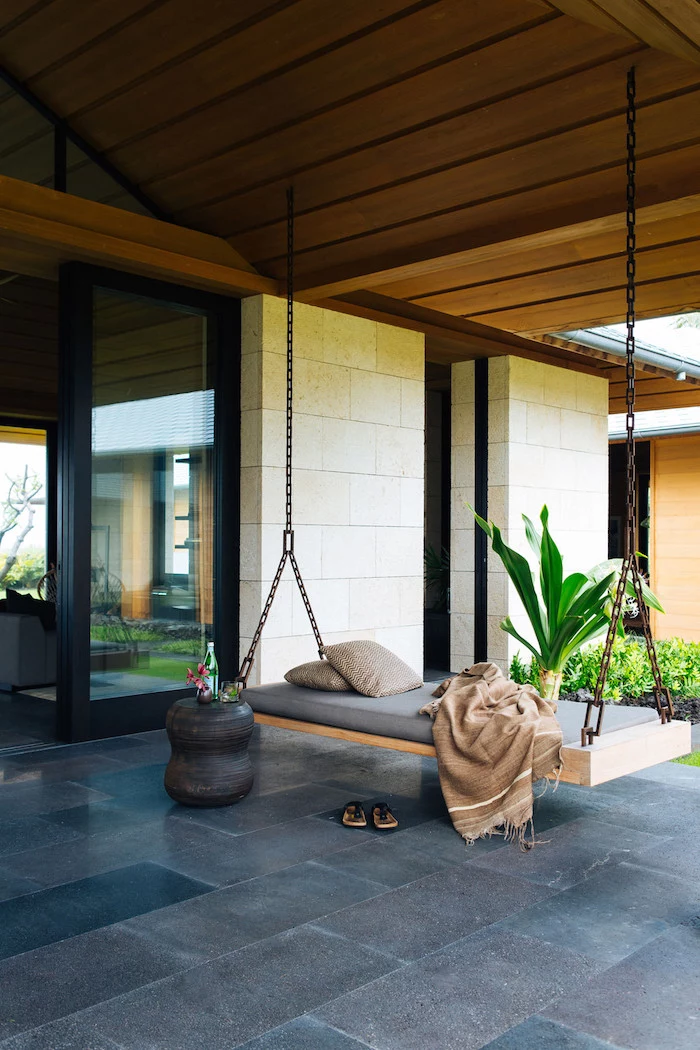 wooden swing, held by metal chains, front porch ideas, tiled floor, beige pillows and blanket
