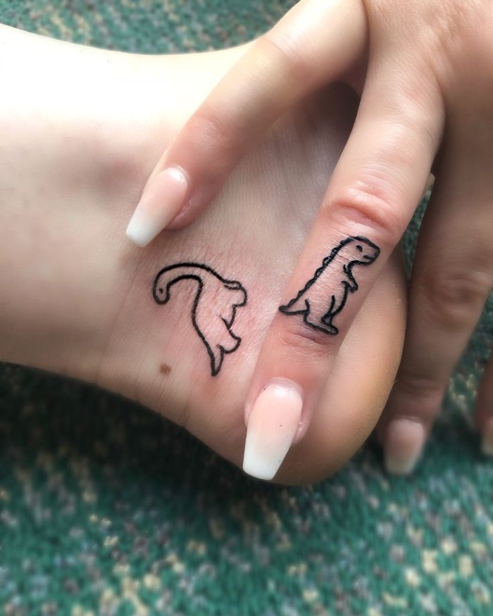 two dinosaurs, matching tattoos, ankle tattoo, finger tattoo, long whte nails, green background