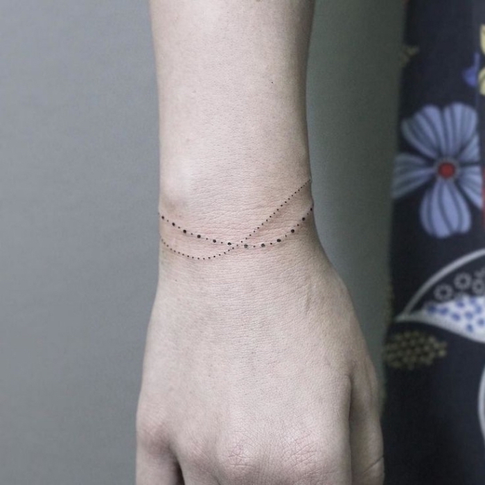dotted bracelet, wrist tattoo, key tattoos, floral shirt, grey background