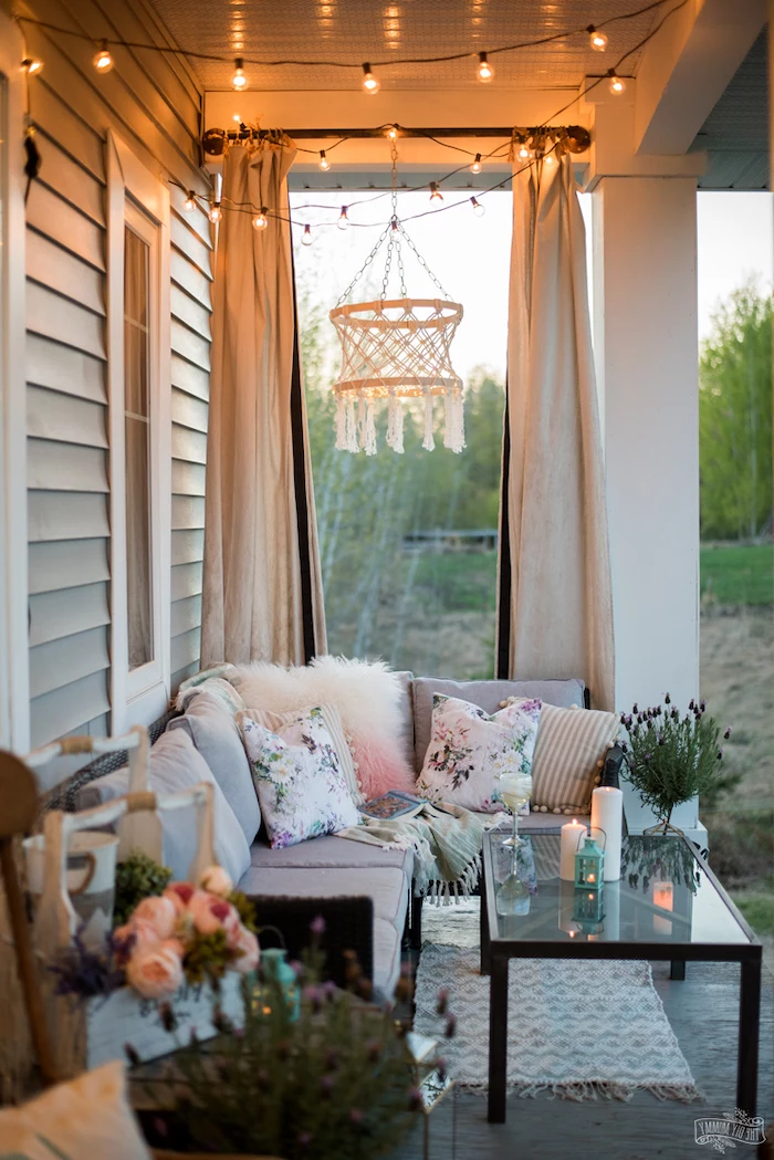 screened in porch designs, strings of lights, grey sofa, glass coffee table, flower bouquets