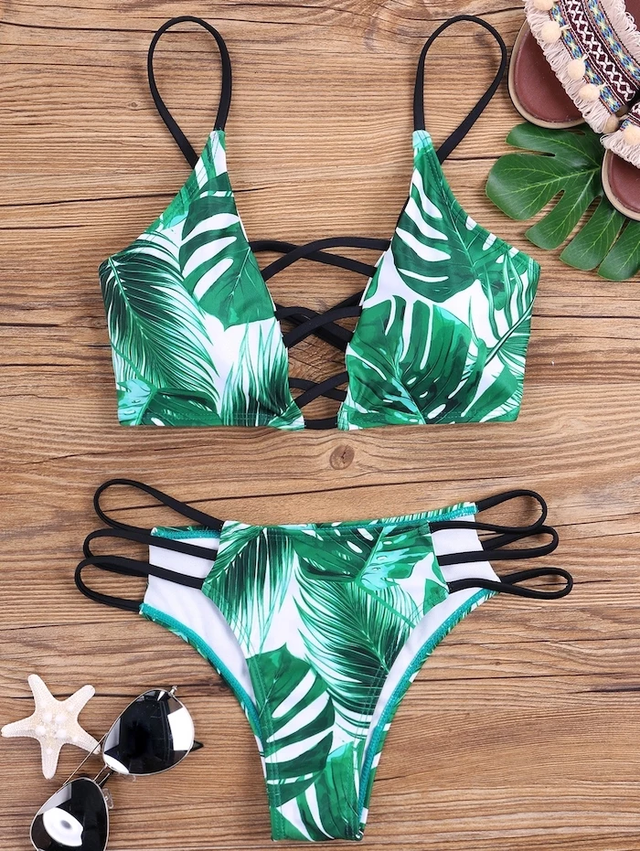 two piece, green palm leaves print, black straps, wooden background, kids bathing suits