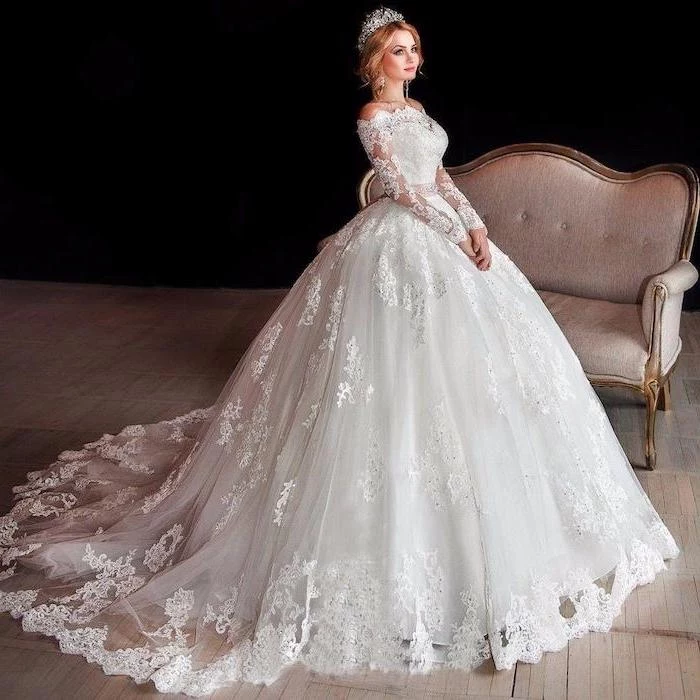 blonde hair, in a low updo, lace wedding dress with cap sleeves, grey sofa, lace and tulle