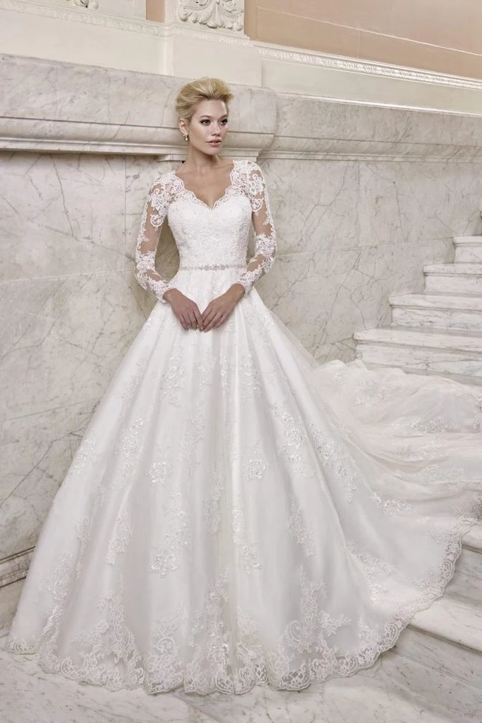 blonde hair, in a low updo, marble staircase, lace wedding dress with cap sleeves, v neckline