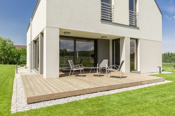 wooden floor, outdoor covered patio, metal garden furniture, green grass field