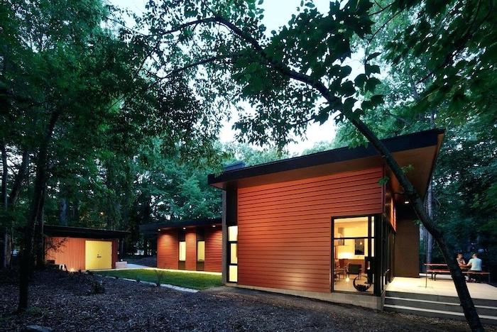 tiled floor, wooden benches and table, gravel and green grass, tall trees, outdoor covered patio