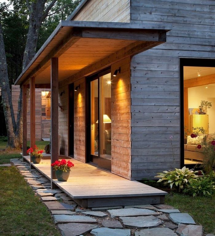 wooden house, potted red flowers, tall windows, screened in porch furniture, stone pathway