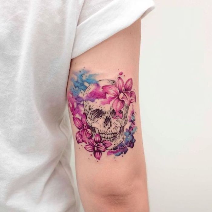 delicate female tattoos, back of arm, watercolour tattoo, skull surrounded by flowers, white shirt