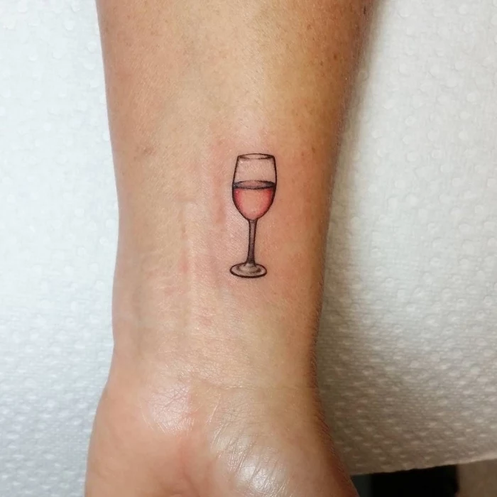 red wine glass, wrist tattoo, white paper, hidden tattoos