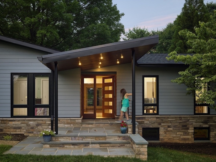 stone tiles floor, brick wall, black metal columns, tall door, small porch ideas, potted plants