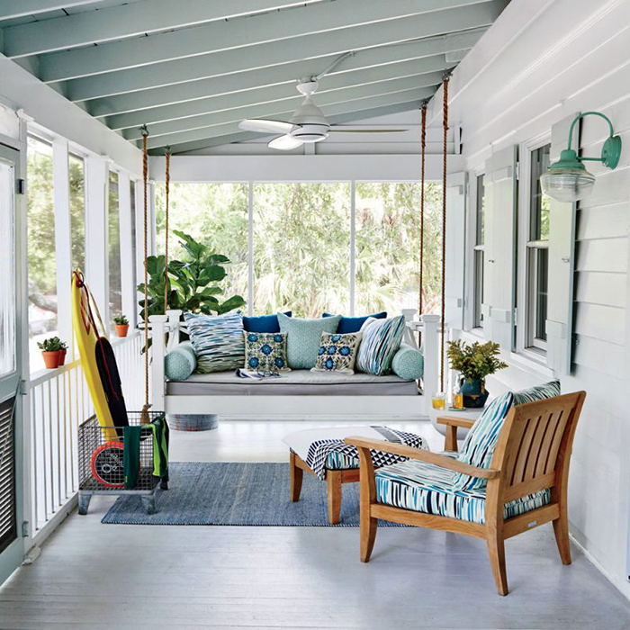 covered porch ideas, wooden swing, grey cushions, colourful throw pillows, wooden chair, blue rug
